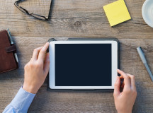 Closeup shot of a woman hands holding digital tablet. Businesswoman is holding a palmtop on desk at office. Blank scrren to 
put it on your own design
